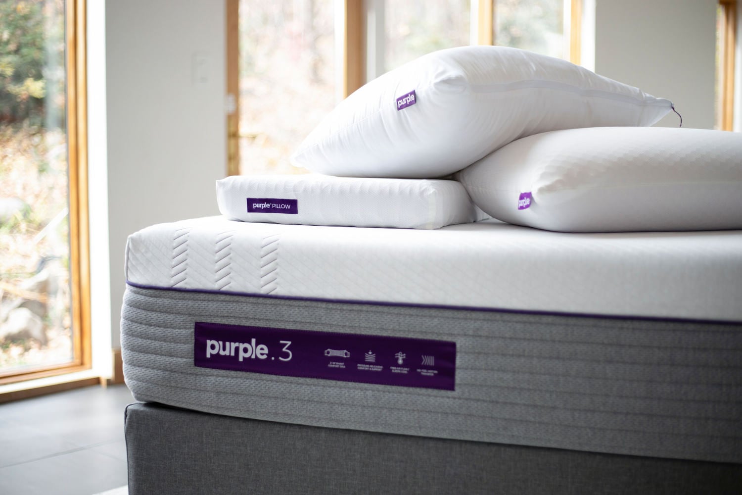 A Purple mattress and pillows by a window
