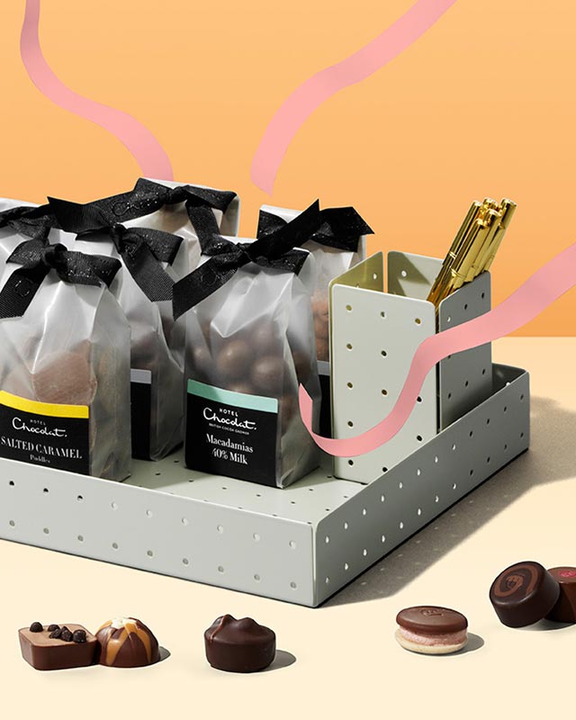 Gift basket with assorted chocolate packages and loose chocolates on a two-tone background