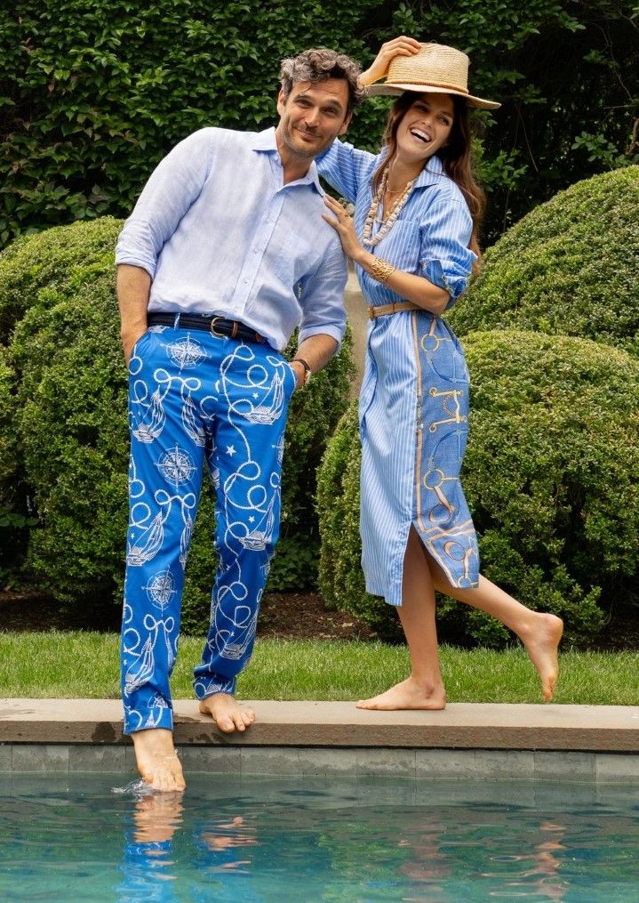 Man and woman in matching blue outfits smiling by a pool