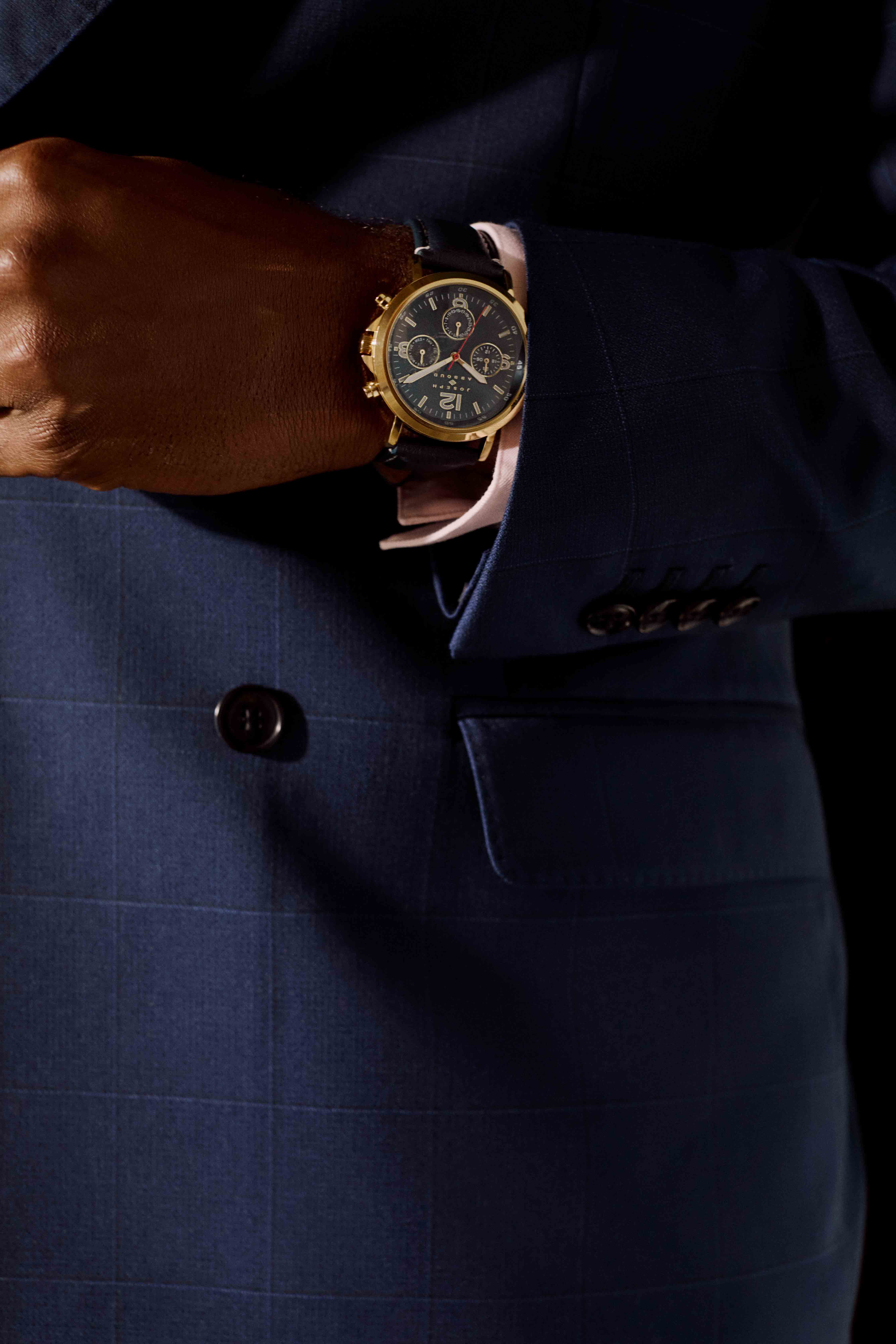 Close-up of a man's wrist wearing a luxury watch with a dark suit
