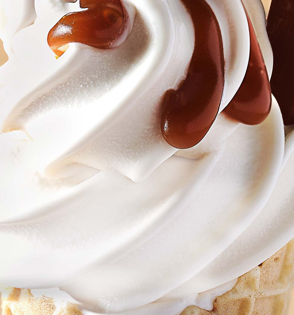 Close-up of vanilla soft serve ice cream topped with caramel sauce