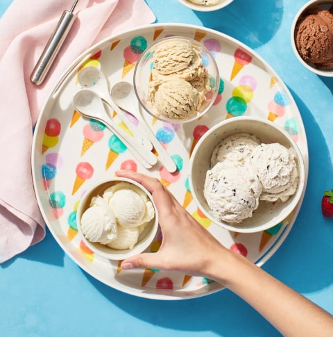 Round serving tray with ice cream motif  with scoops of ice cream and spoons, surrounded by bowls containing more ice cream