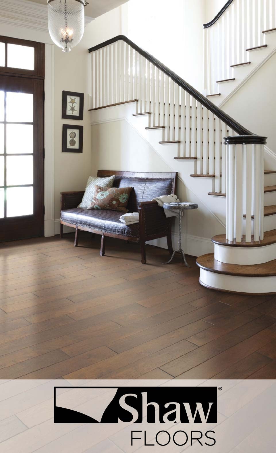 Elegant foyer with wooden floors by Shaw Floors, featuring a staircase, bench, and artwork