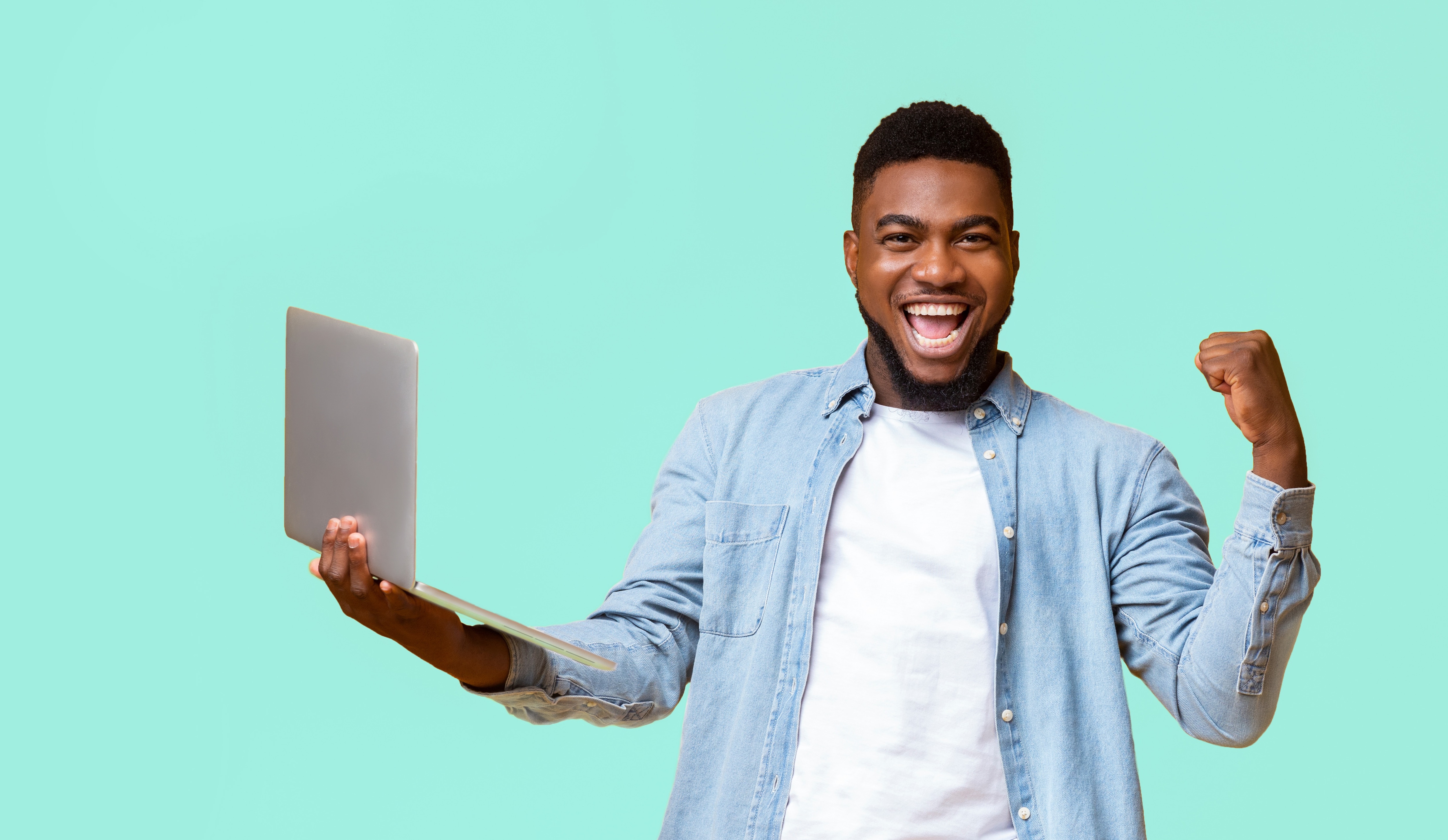 Happy man holding a laptop and flexing arm in victory against a light blue background