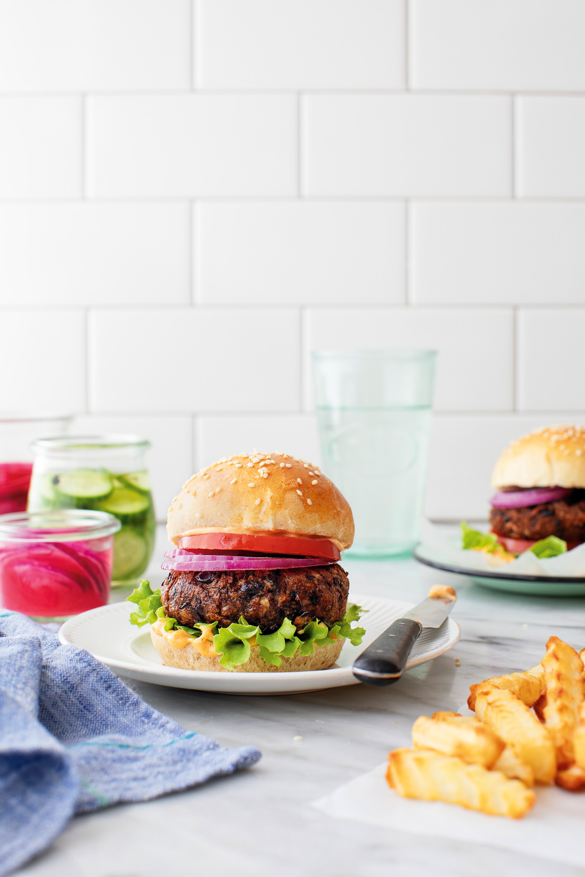 Burger végétarien servi avec frites et garnitures sur une table en cuisine