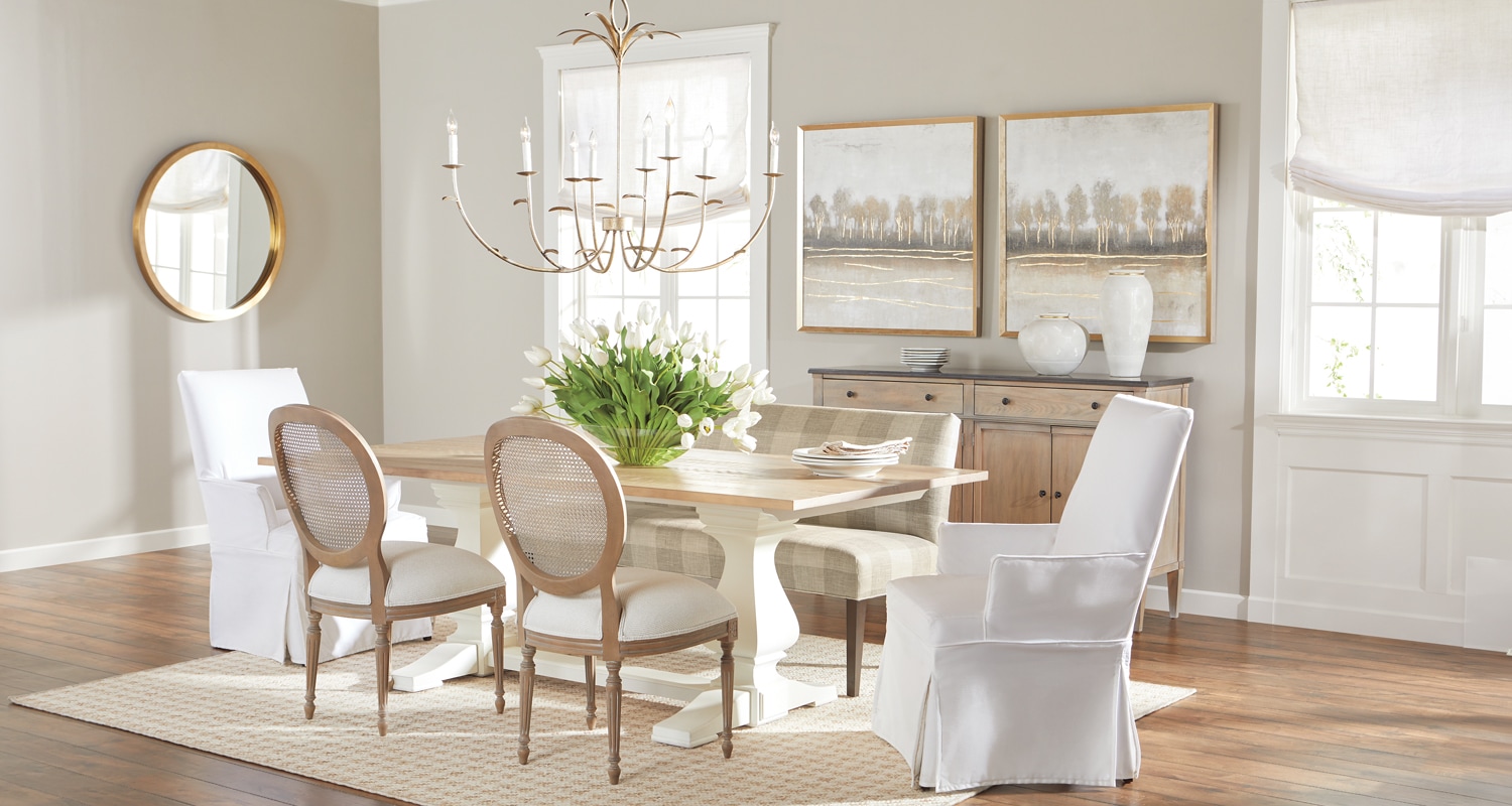 Elegant dining room with table set for six, chandelier, mirror, and wooden cabinet