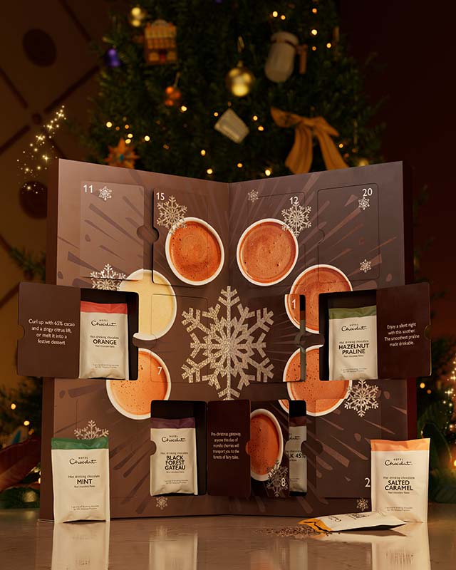 Advent calendar with open doors displaying tea bags, set against a festive background with lights