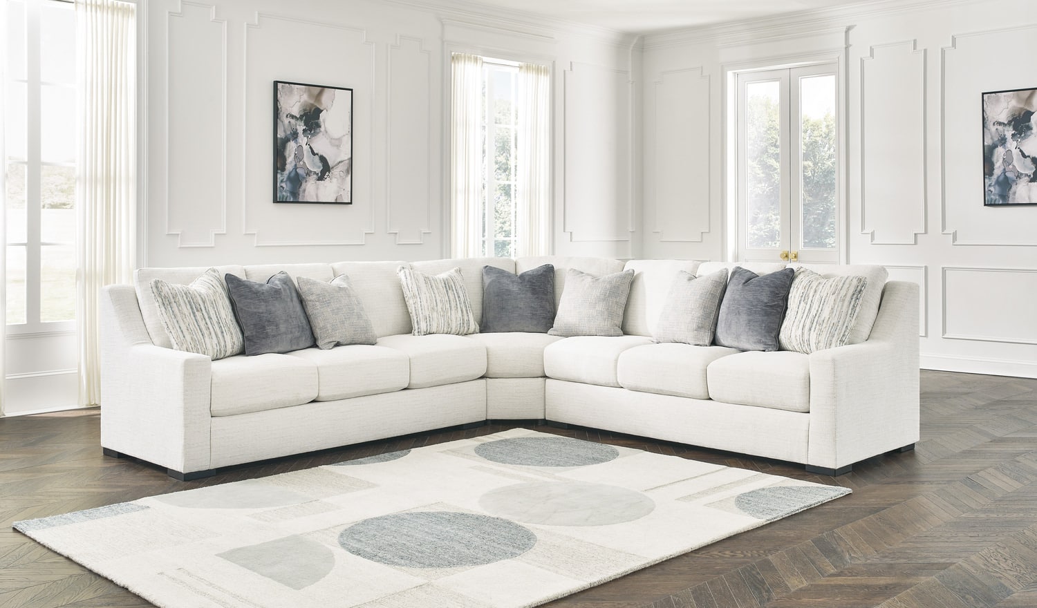 White sectional sofa with gray cushions in a bright living room with white cabinets and framed art
