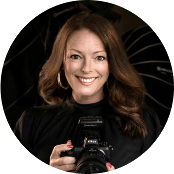 Smiling woman holding a camera with a blurred black background