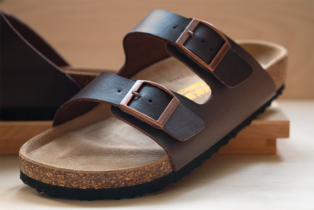 Sandale à brides en cuir marron sur un présentoir en bois