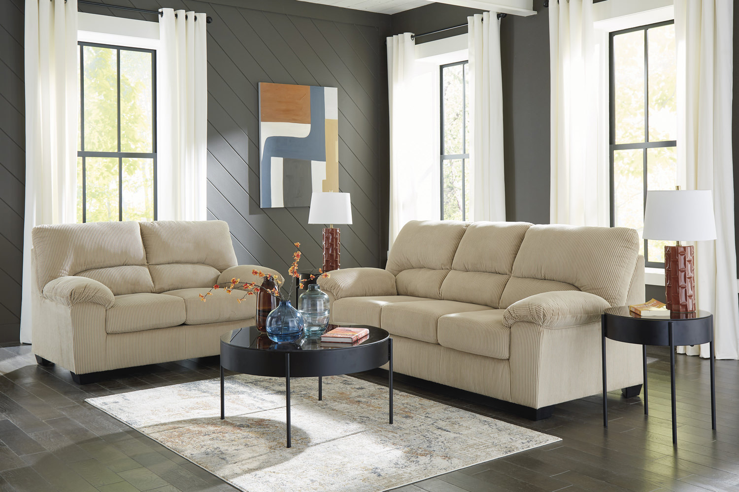 Elegant living room with two beige sofas, a glass coffee table, and modern decor in a gray-toned space