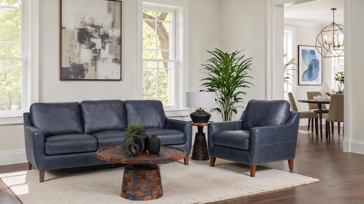 Elegant living room with a blue sofa set, rug, and adjoining dining area visible in the background