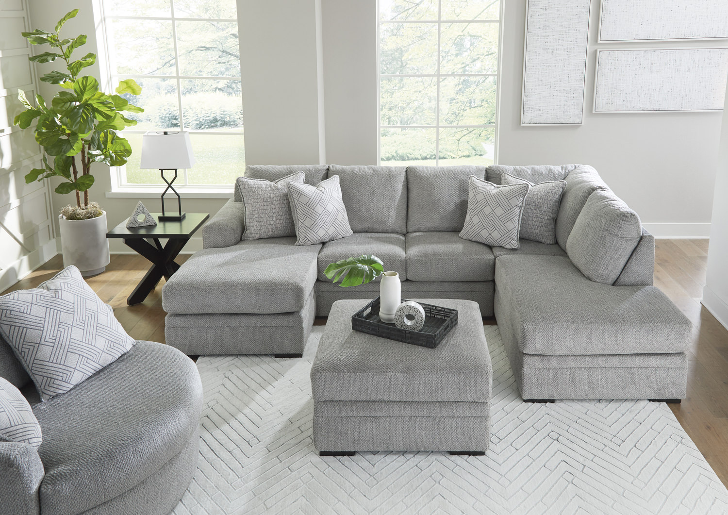 Modern living room with a large grey sectional sofa, white rug, and natural light