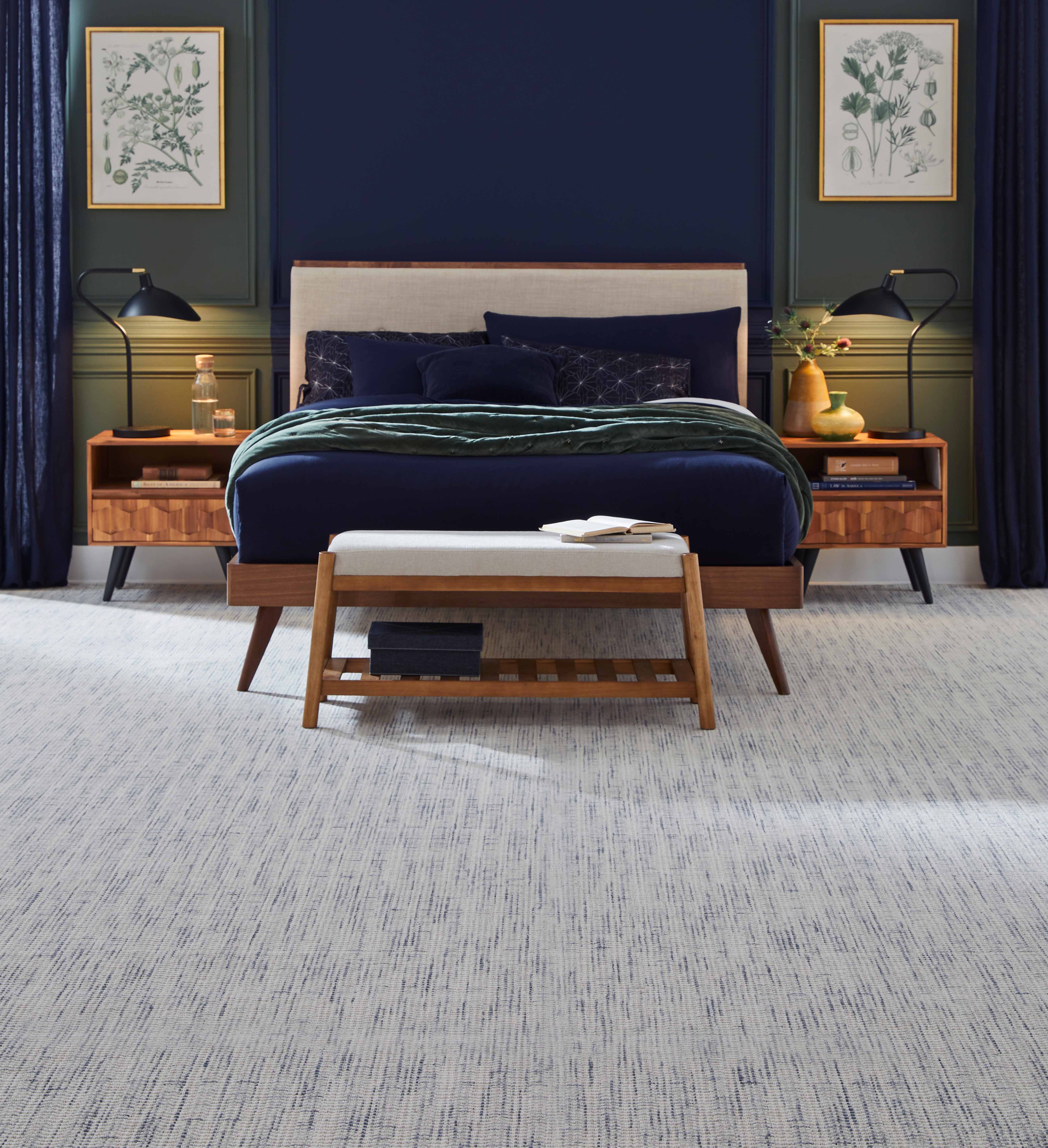 Elegant bedroom with a blue theme, featuring a plush bed, two bedside tables, and decoratively framed artworks