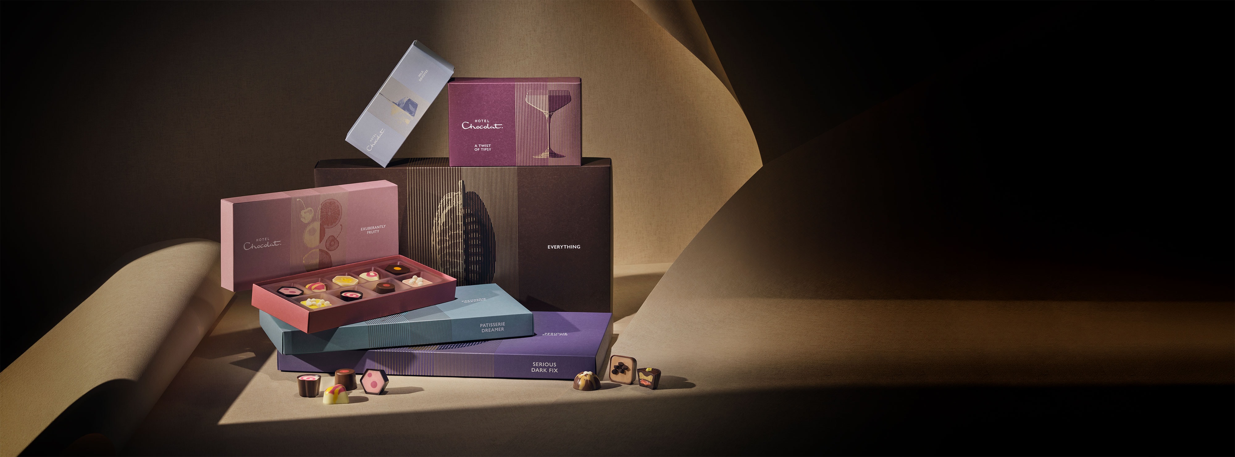 A small model of a bedroom scene with a bed, dresser, and writing desk, illuminated in a dark background