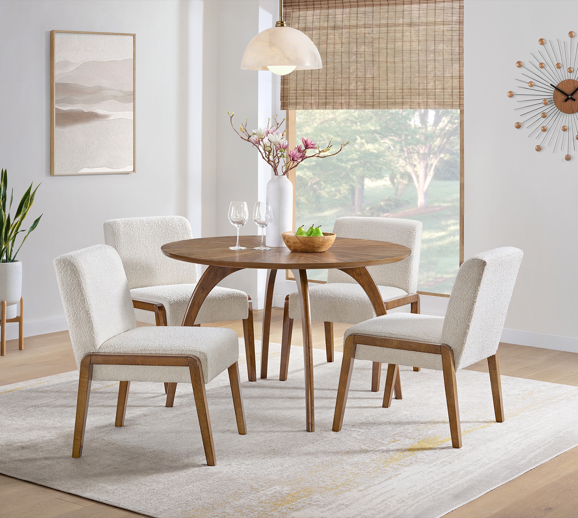 Modern dining room with a round wooden table, four chairs, and stylish decor in a bright, airy space