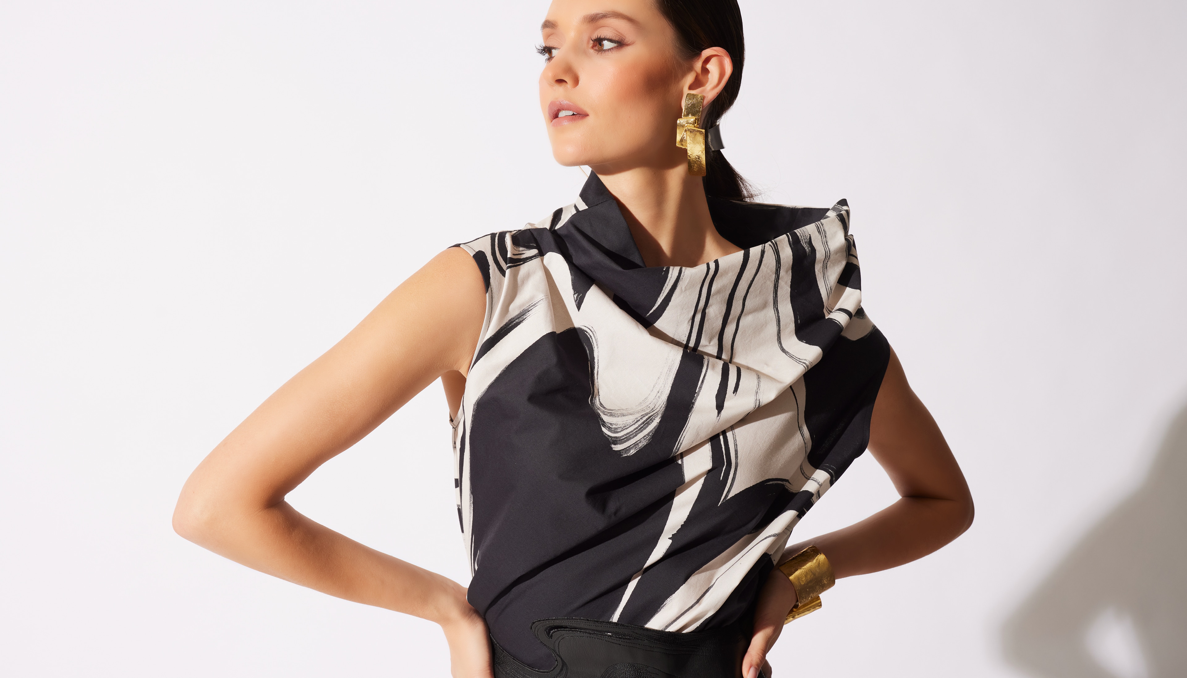 Woman in a stylish black and white ruffled top posing with hand on hip