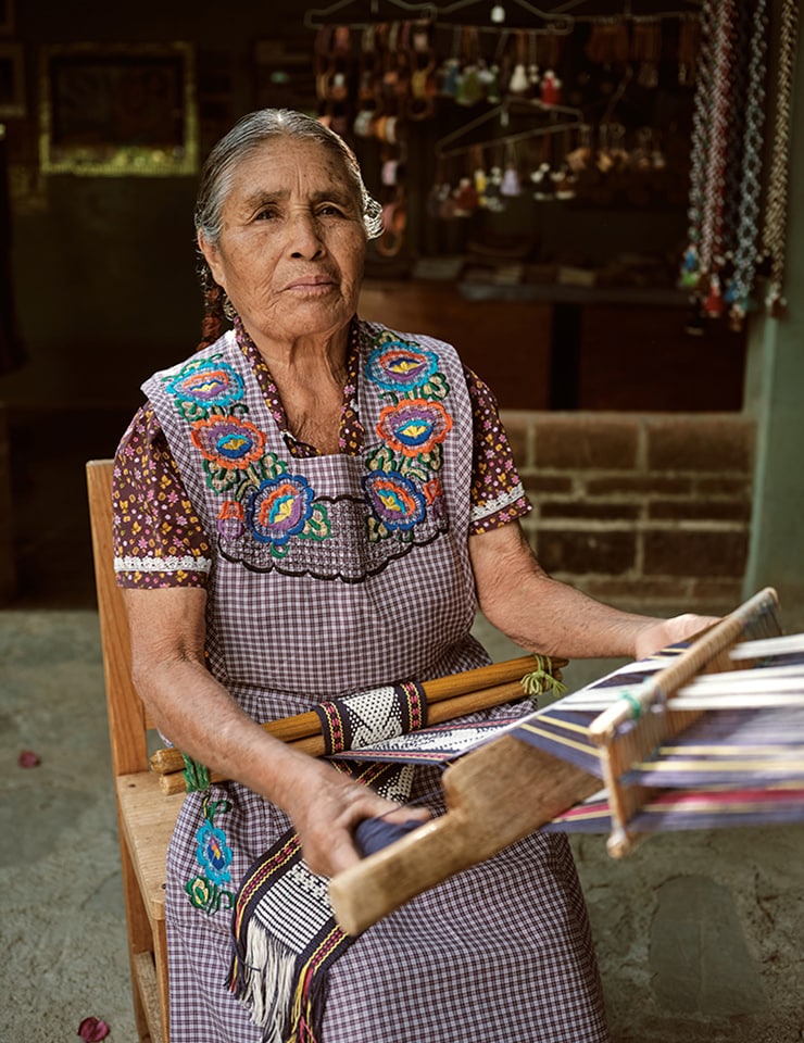 Elderly woman in traditional attire weaving on a loom