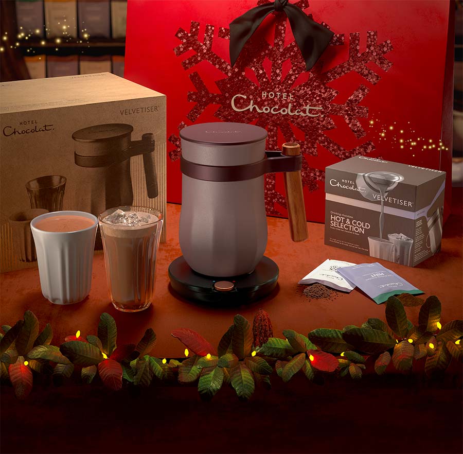 Holiday-themed coffee setup with a grinder, two drinks, and festive lights