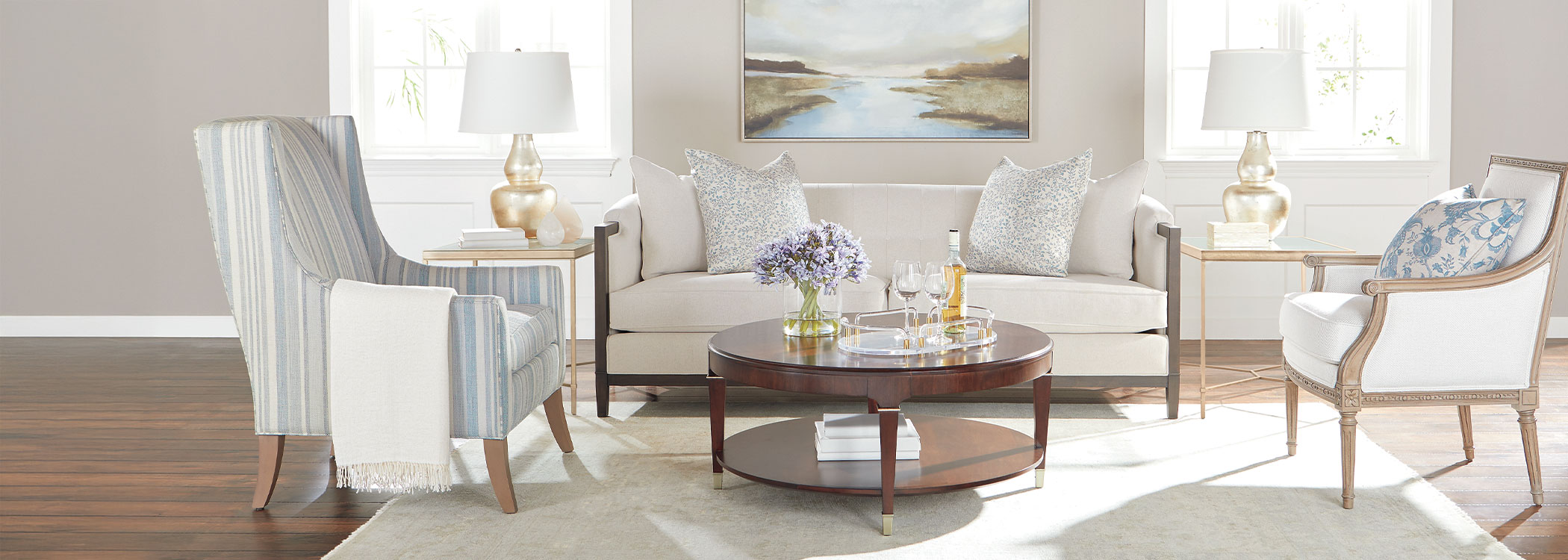 Elegant living room with two chairs, a sofa, a wooden coffee table, and a wall painting