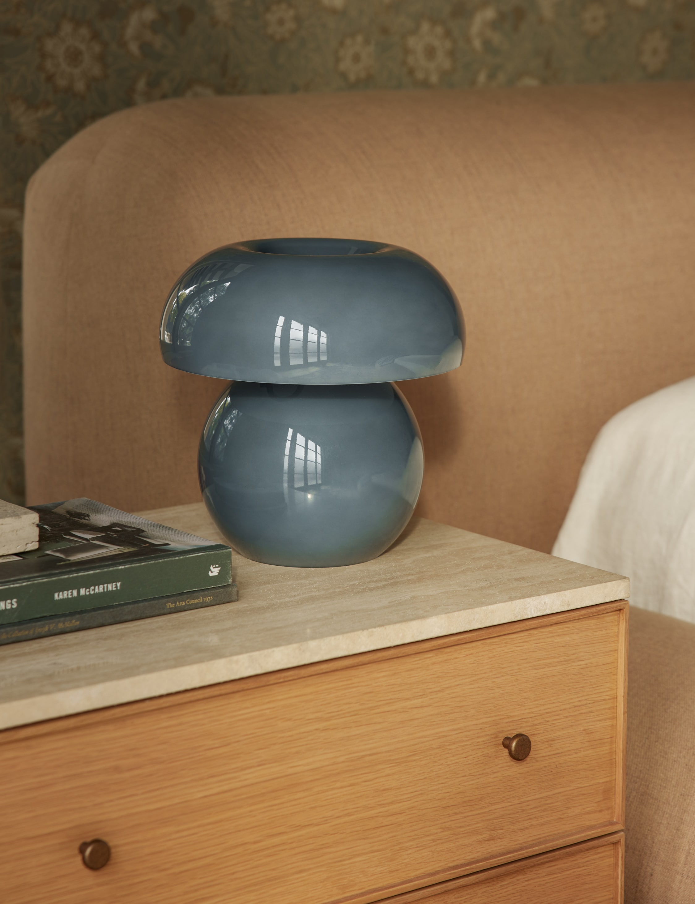 Blue mushroom-shaped lamp on a wooden nightstand next to a bed