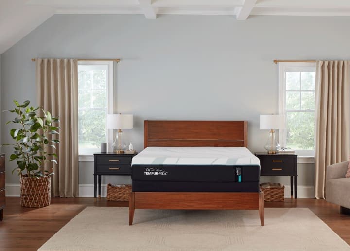 Minimalist bedroom with a wooden double bed, two side tables, and a plant near the window
