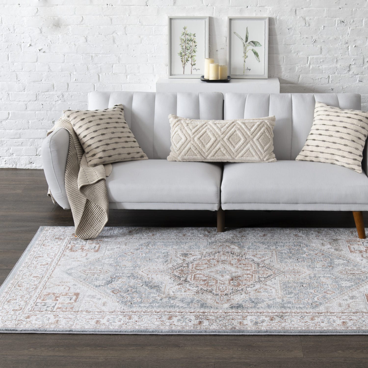 Modern living room with a gray sectional sofa, decorative pillows, and a white brick wall