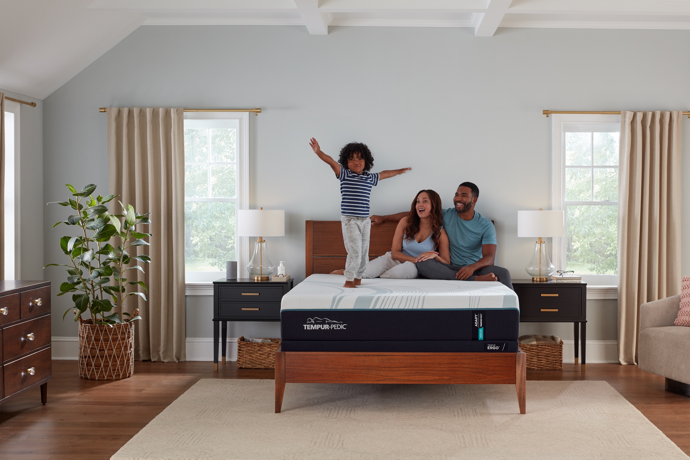 Family with a child having fun on a bed in a well-lit, cozy bedroom