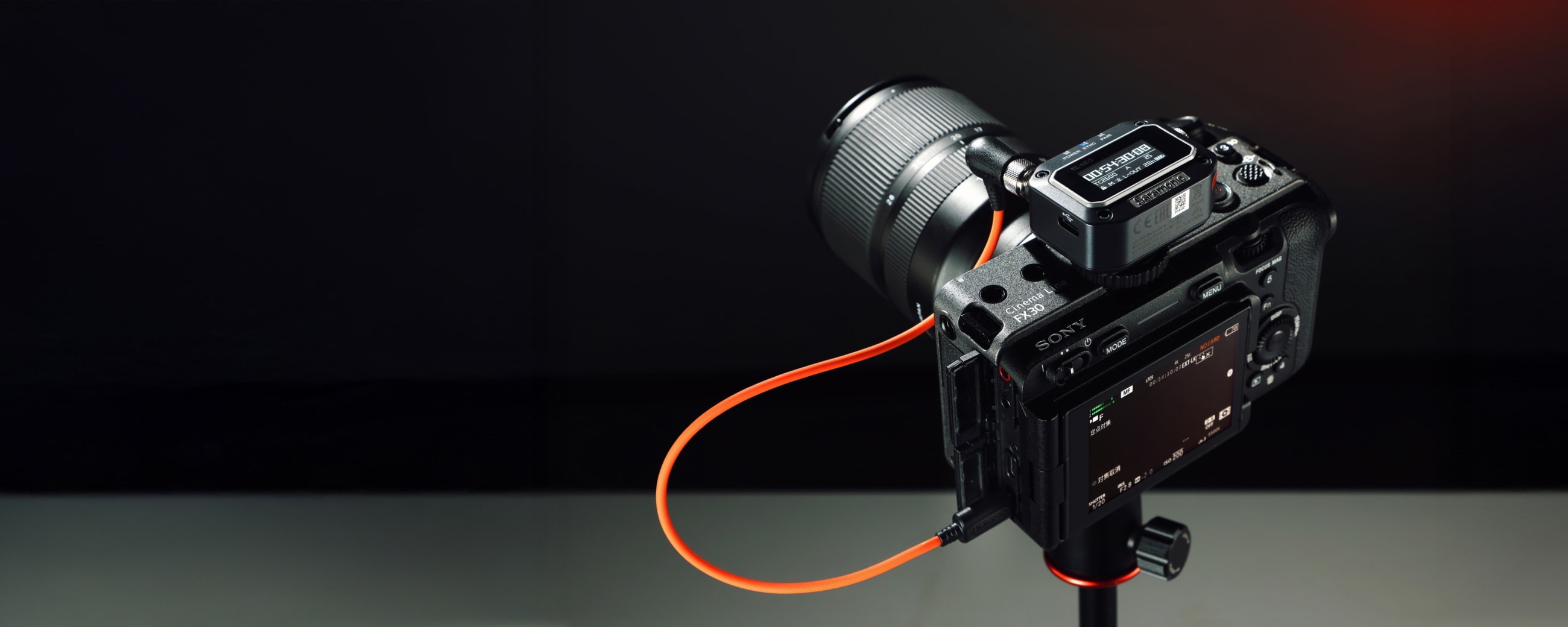 Professional digital camera with a cable on a tripod against a dark background