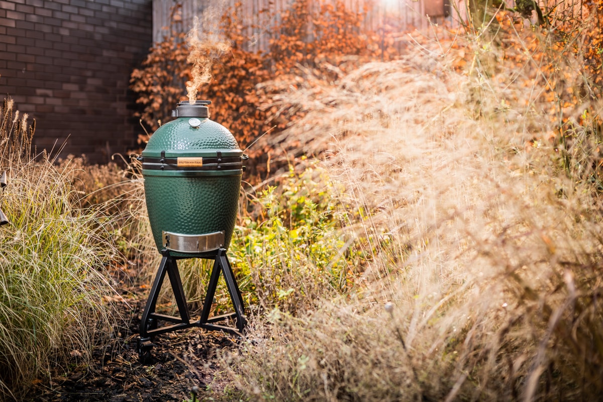 Green ceramic grill in a garden surrounded by tall, dry grass