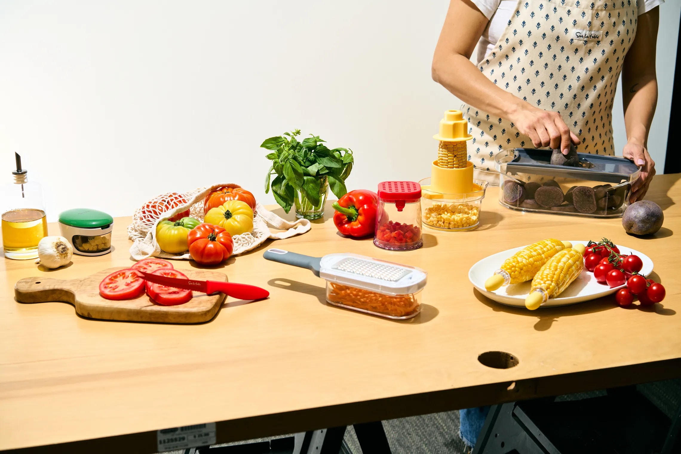 Person cooking in kitchen with array of fresh ingredients on table