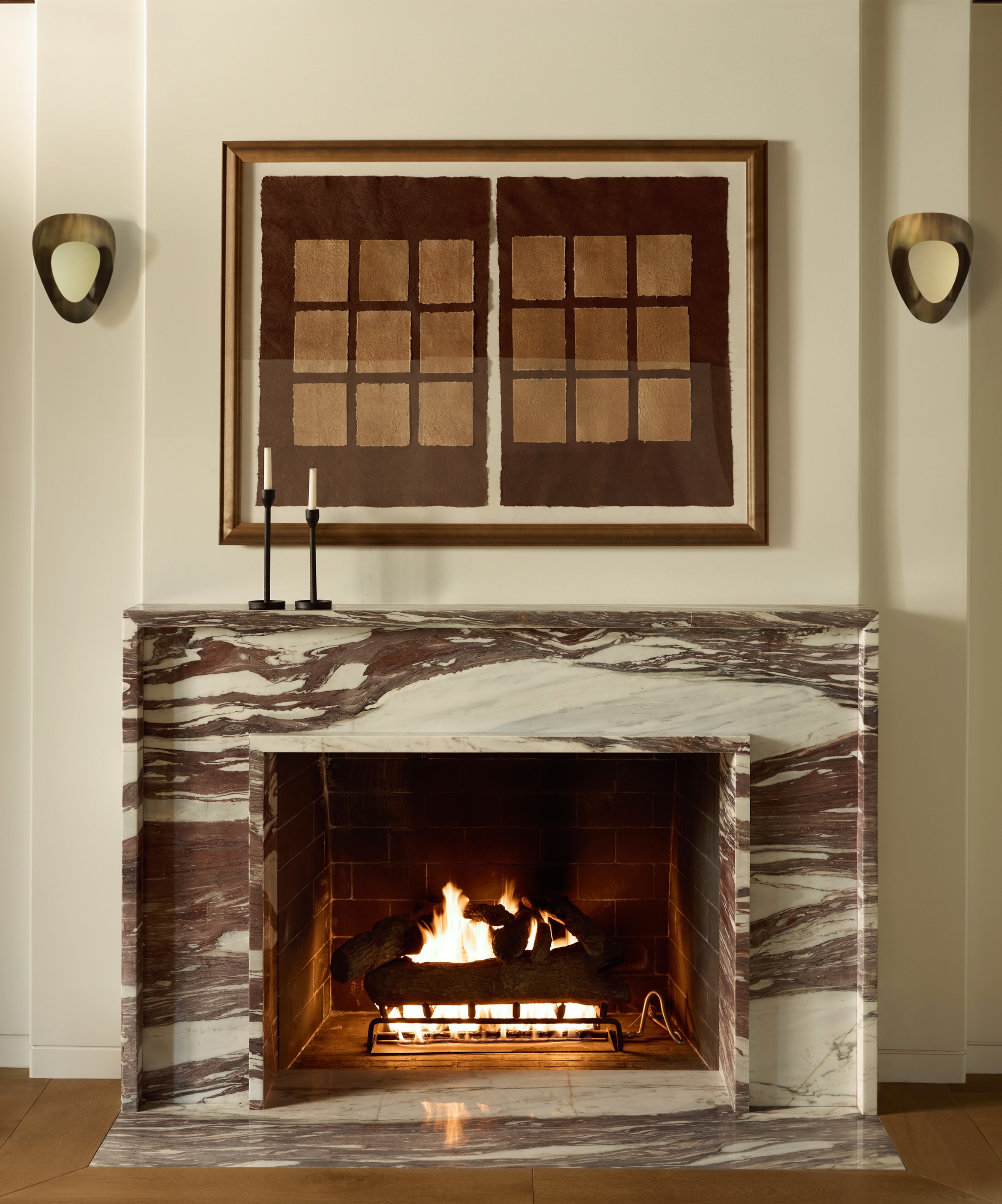 Elegant marble fireplace with lit fire and wall sconces in a stylish interior