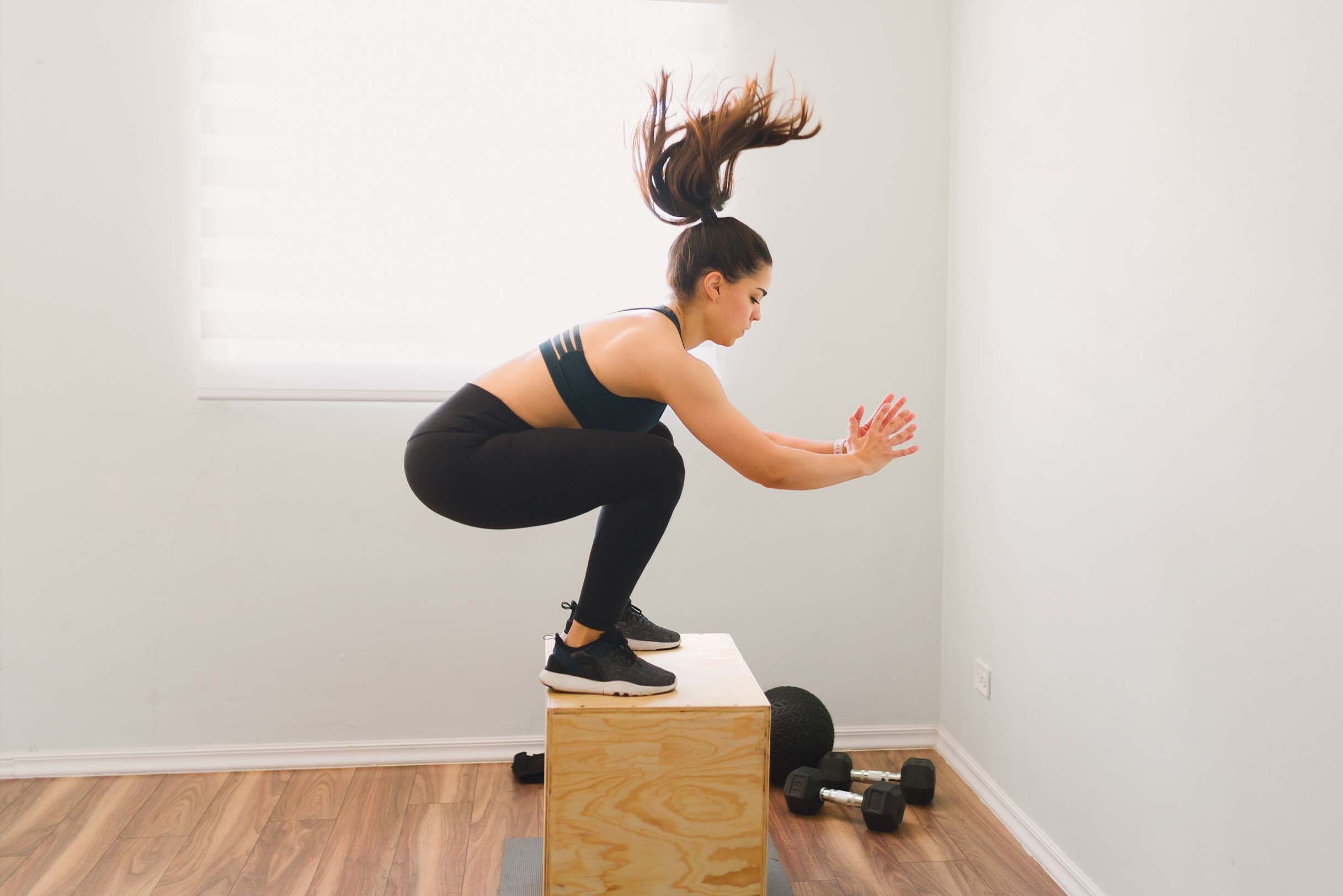 Femme faisant un saut de boîte en salle de sport