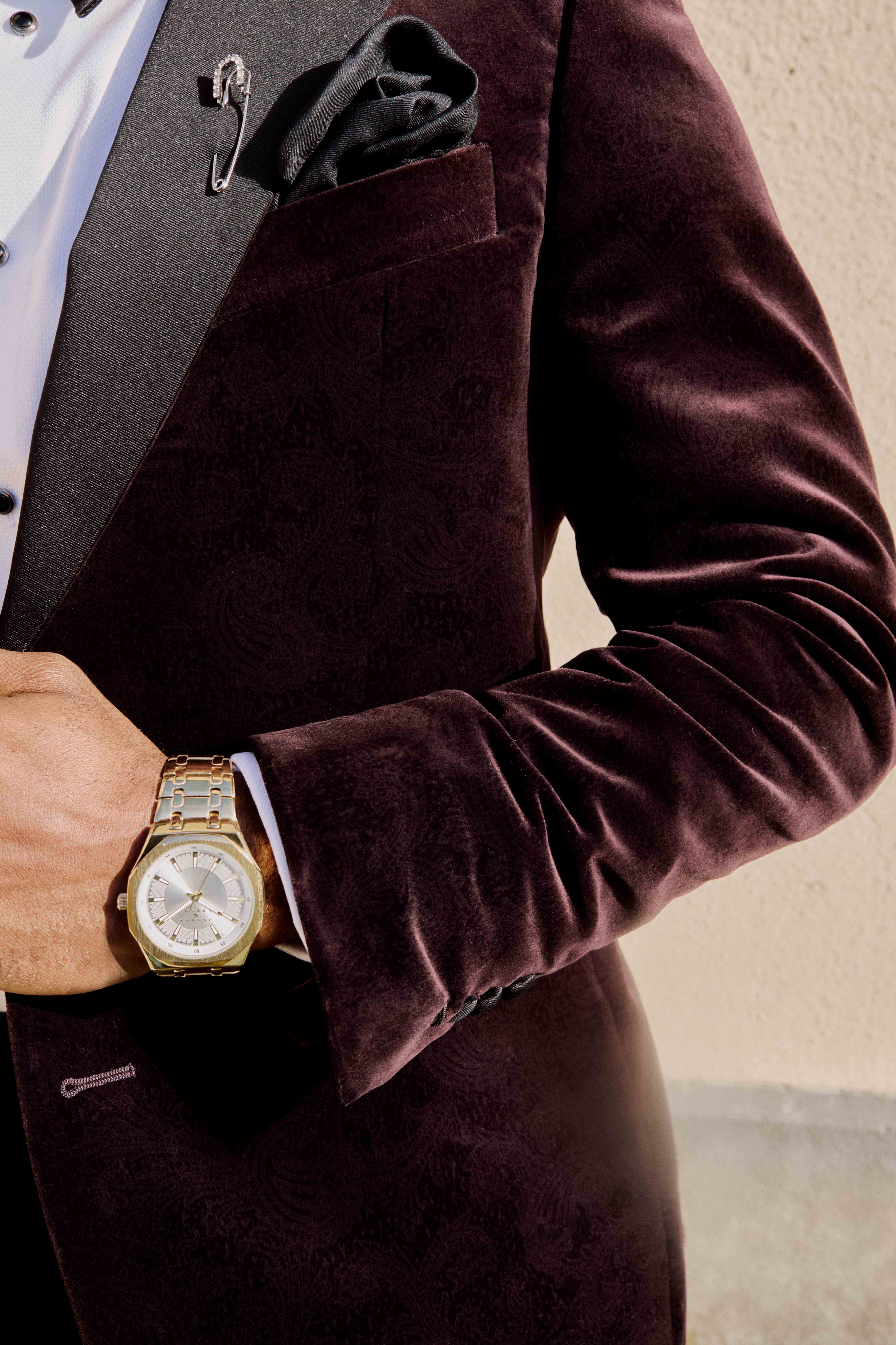 Close-up of a man in a velvet blazer checking a stylish wristwatch