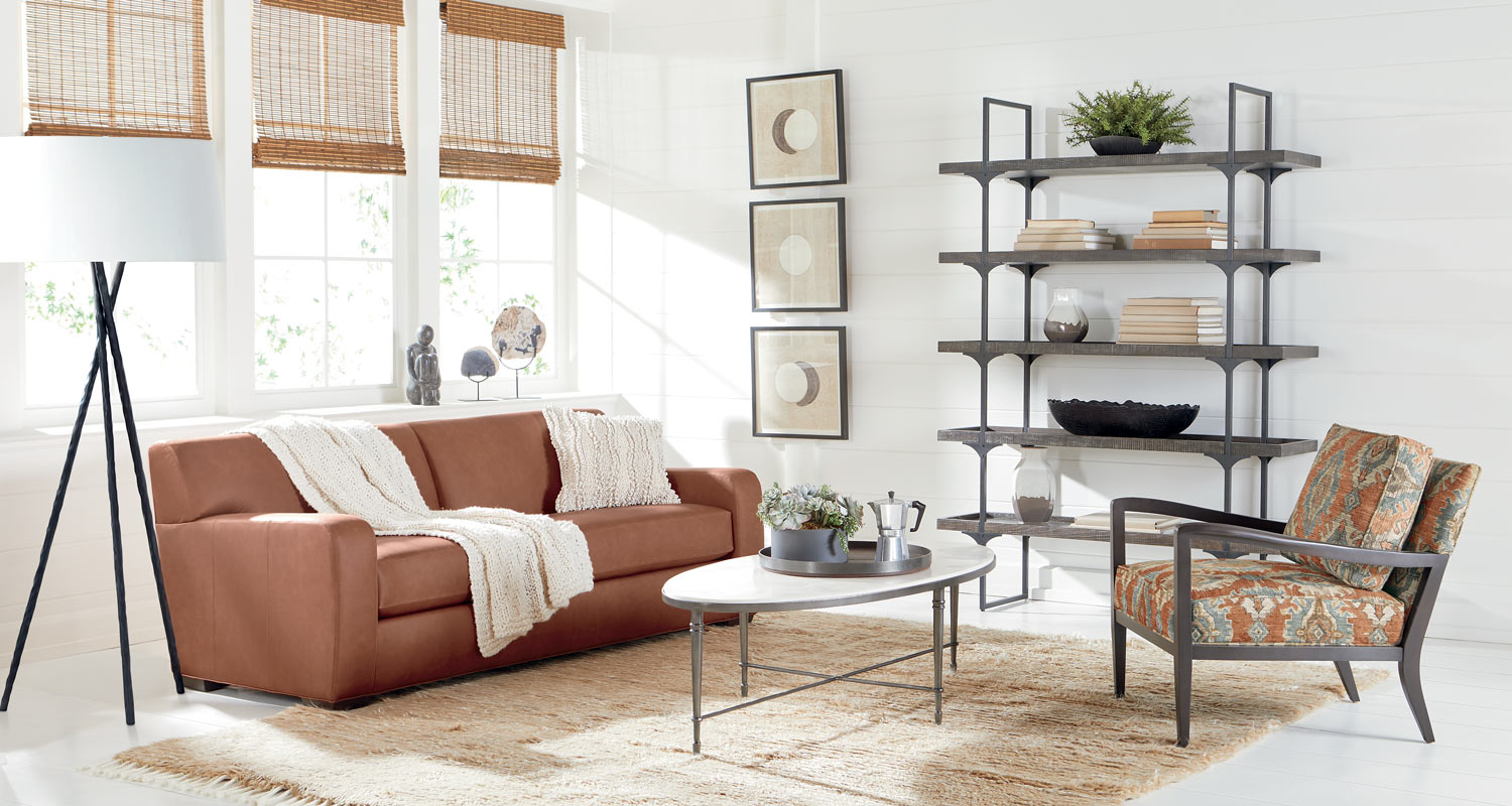 Modern living room with brown sofa, chair, coffee table, and shelving unit