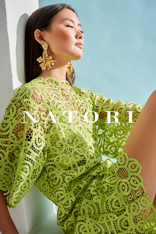Asian woman in green lace dress posing with hand on hip, large floral earrings visible