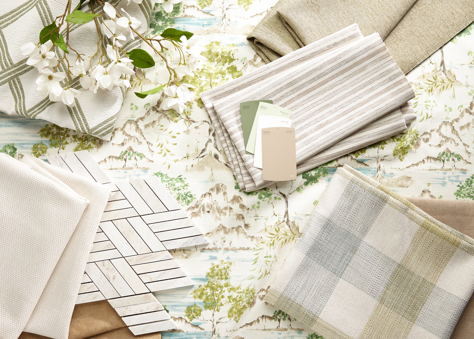 Fabric swatches and paint samples on a floral background with a sprig of white flowers