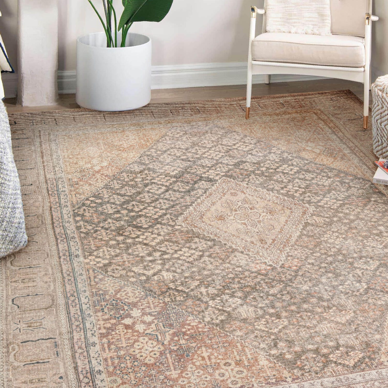 Beige vintage rug on a wooden floor in a cozy room with a white chair and potted plant