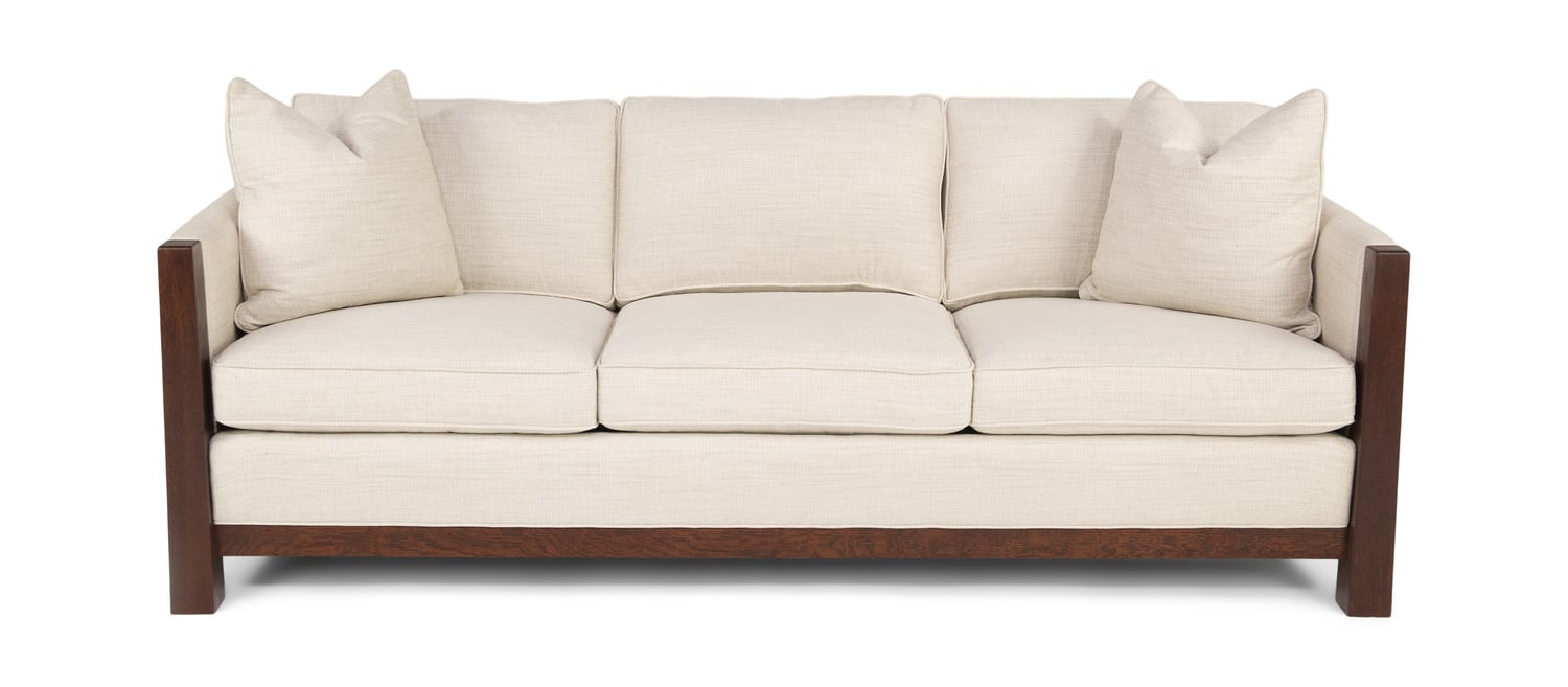 A beige three-seater sofa with brown wooden frame and white cushions