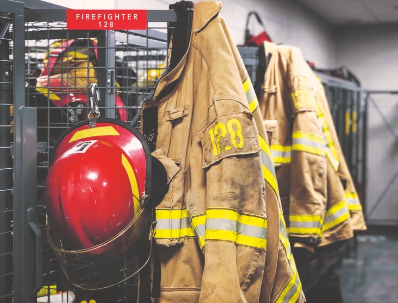 Équipement de pompier, y compris veste, casque rouge, affiché sur un rack