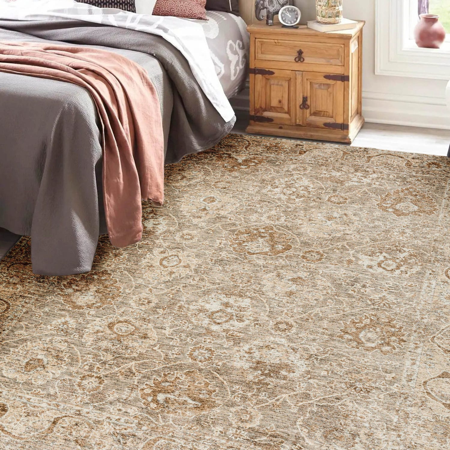 Decorative area rug under a bed with wooden nightstand and gray bedding in a bright room