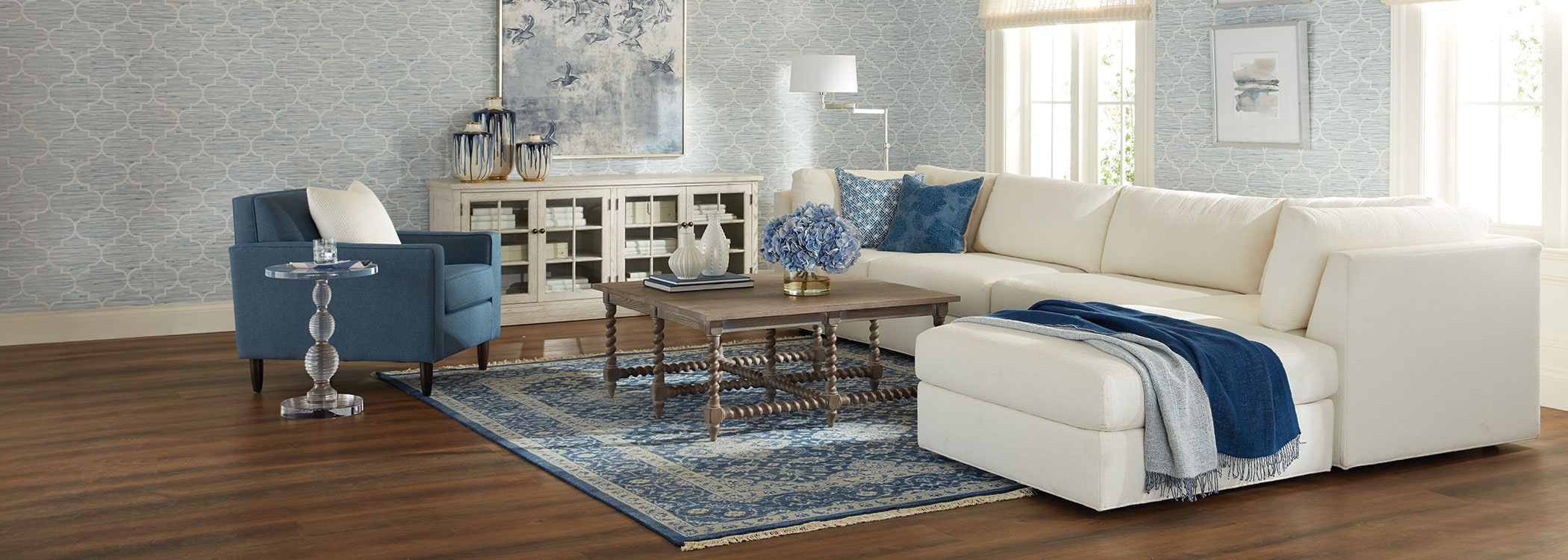 Modern living room with beige sofa, blue armchairs, and wooden coffee table on a blue rug