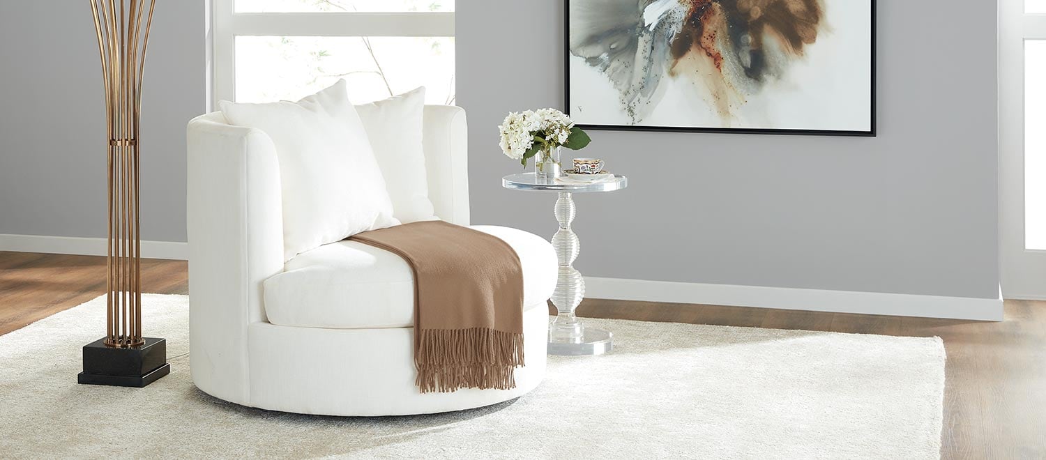 Modern living room with a white round chair, small side table, and abstract wall art