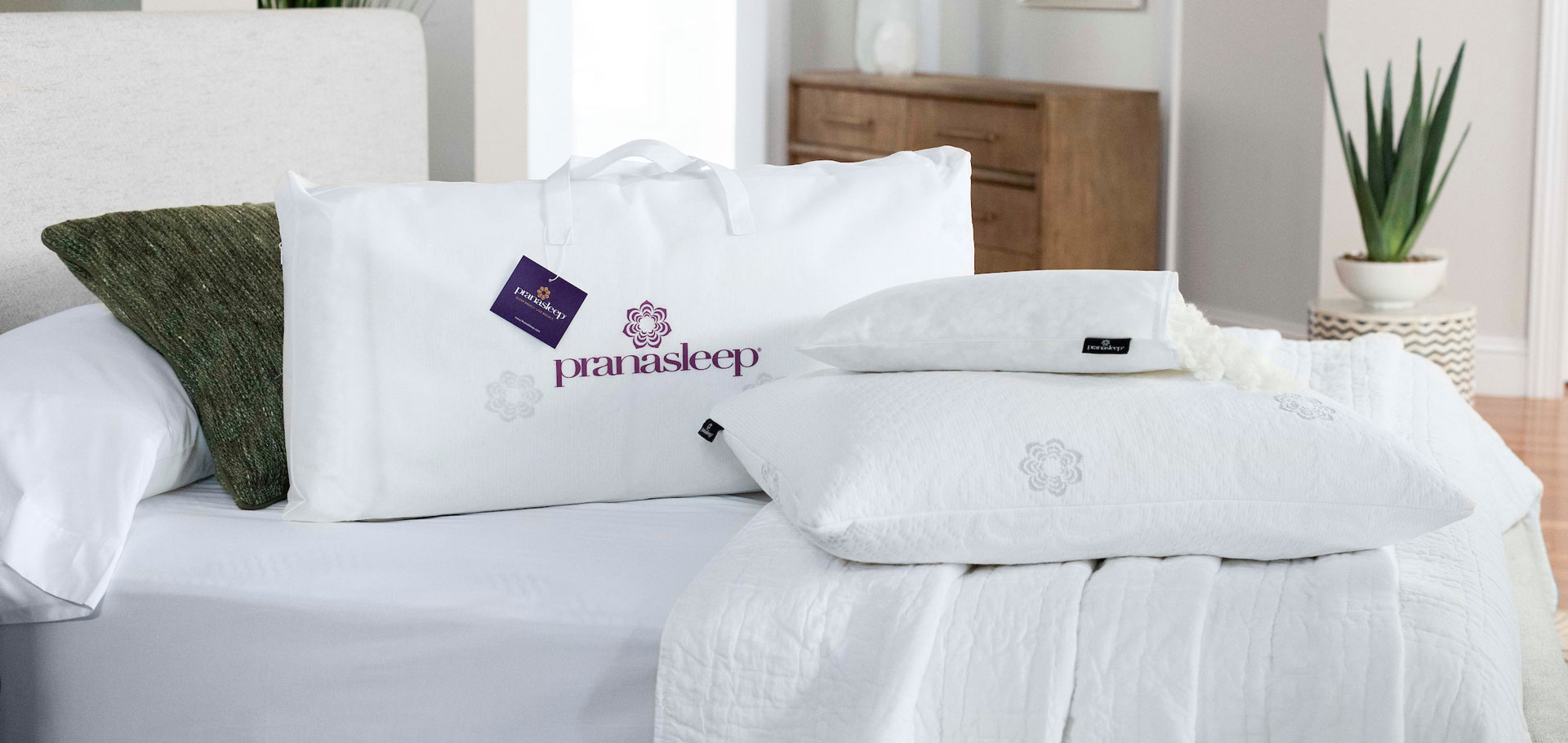 A neatly made bed with white linens and multiple pillows in a bright room