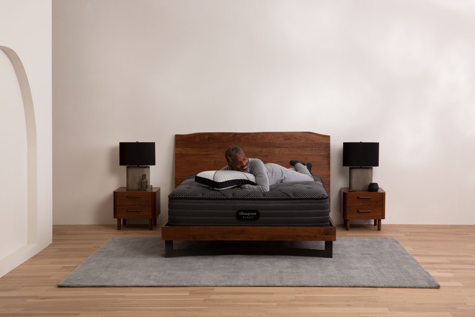 Minimalist bedroom with wooden bed, matching nightstands, and textured rug