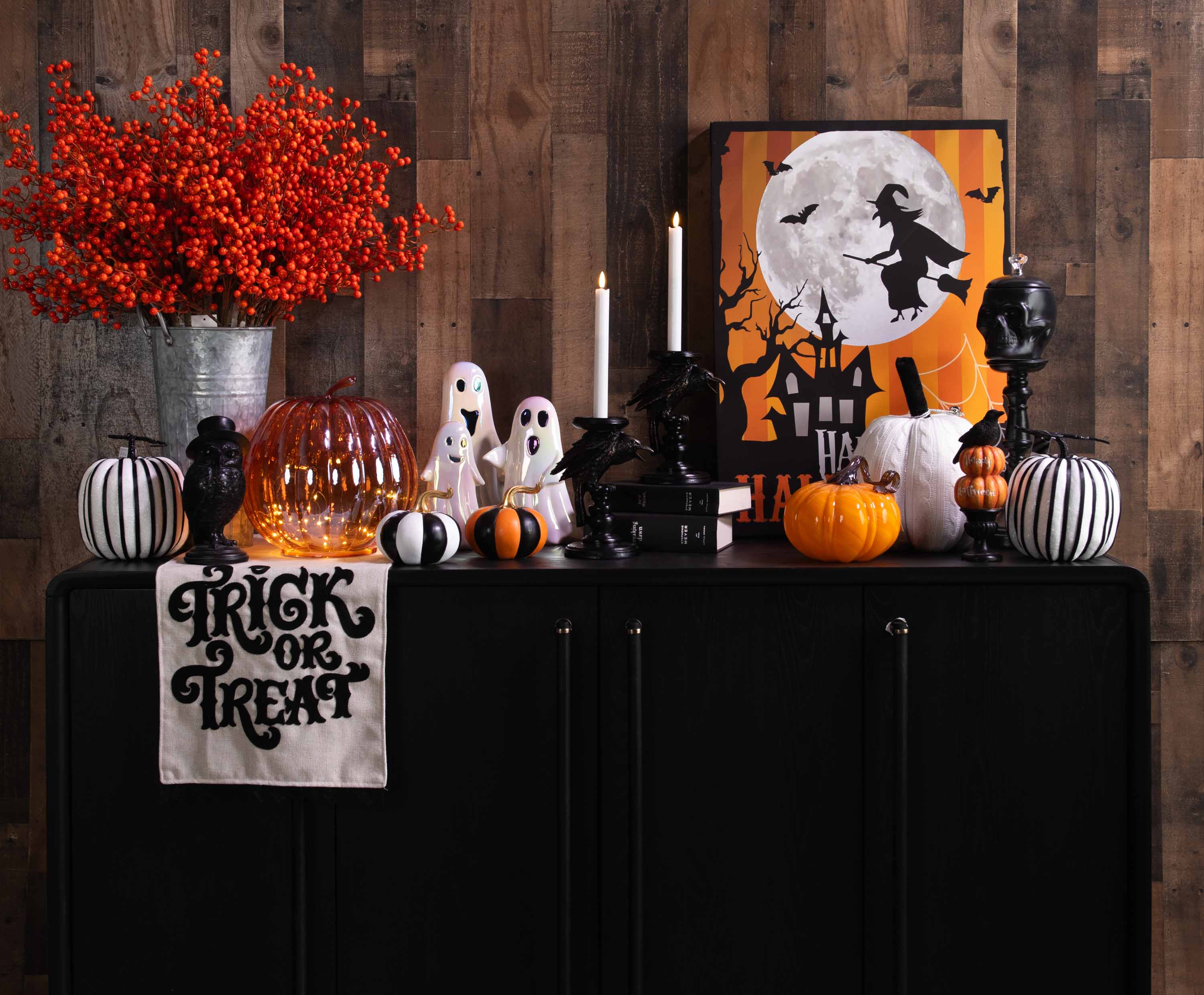 Halloween-themed display with pumpkins, ghost figures, and "Trick or Treat" sign on a cabinet