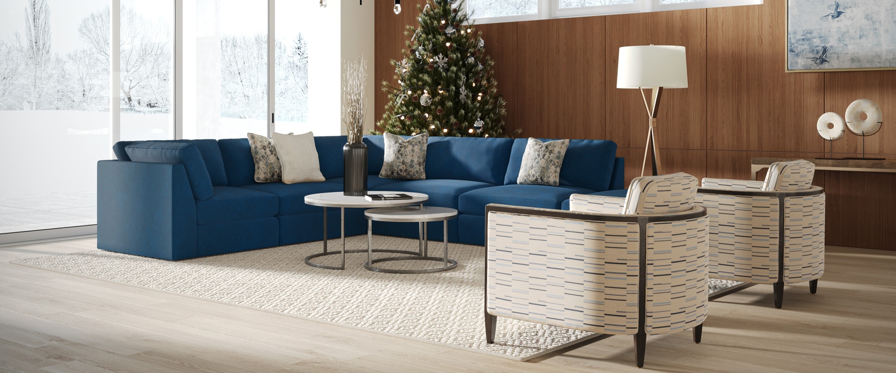 Modern living room with blue sofa, wooden tables, and a Christmas tree by a large window