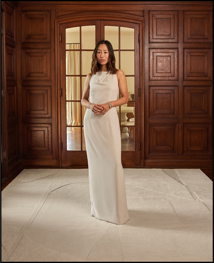 Woman in white dress standing in a room with ornate wooden paneling