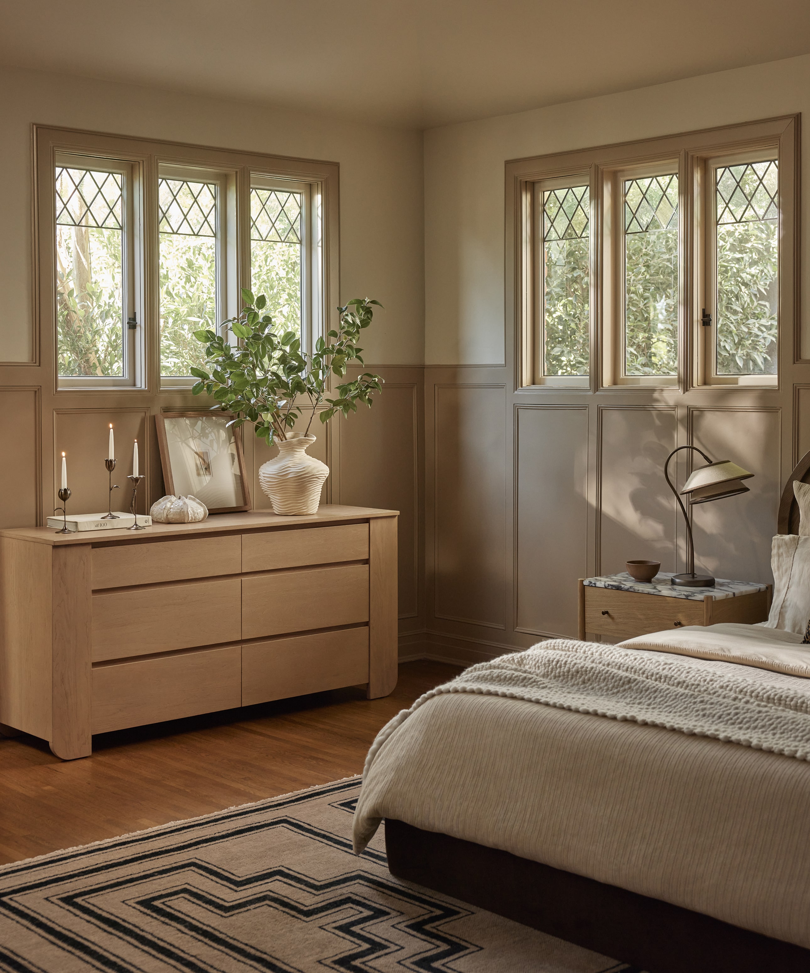 Cozy bedroom with a bed, dresser, and large windows letting in natural light
