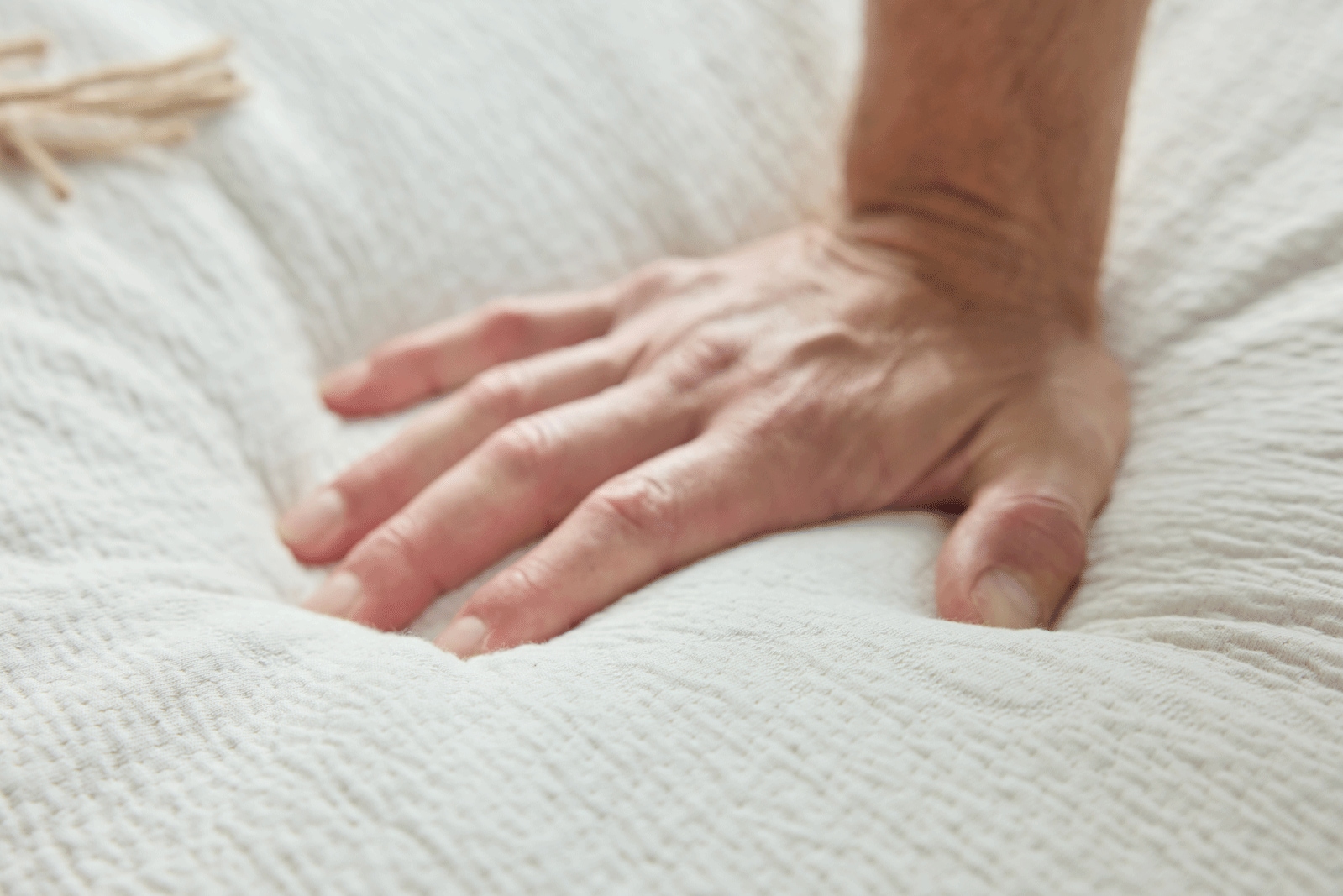 A close-up of a hand resting on a white textured blanket